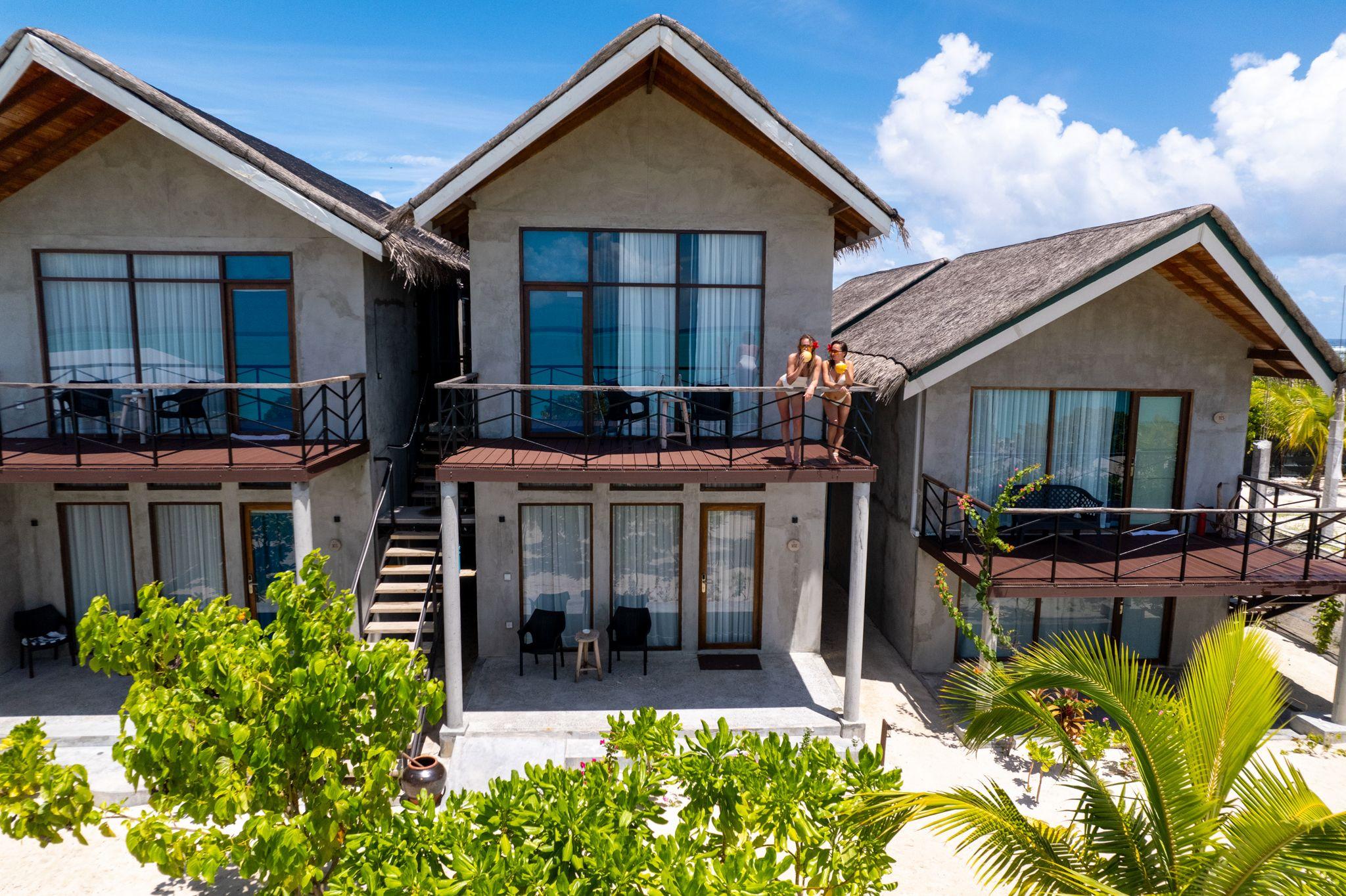Models posing on the balcony in an aerial shot of Araaik Beach Village in the Maldives